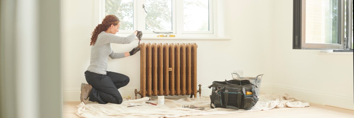 female plumber installing cast iron radiator female plumber installing cast iron radiator